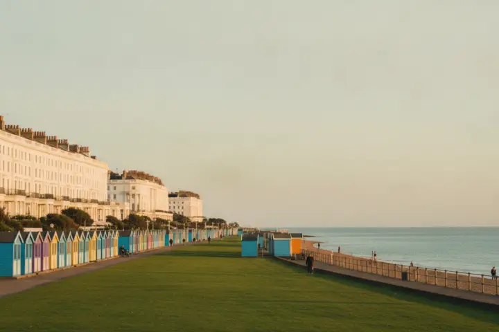 Colourful beach huts on Hove seafront lawns with white Regency terraces behind